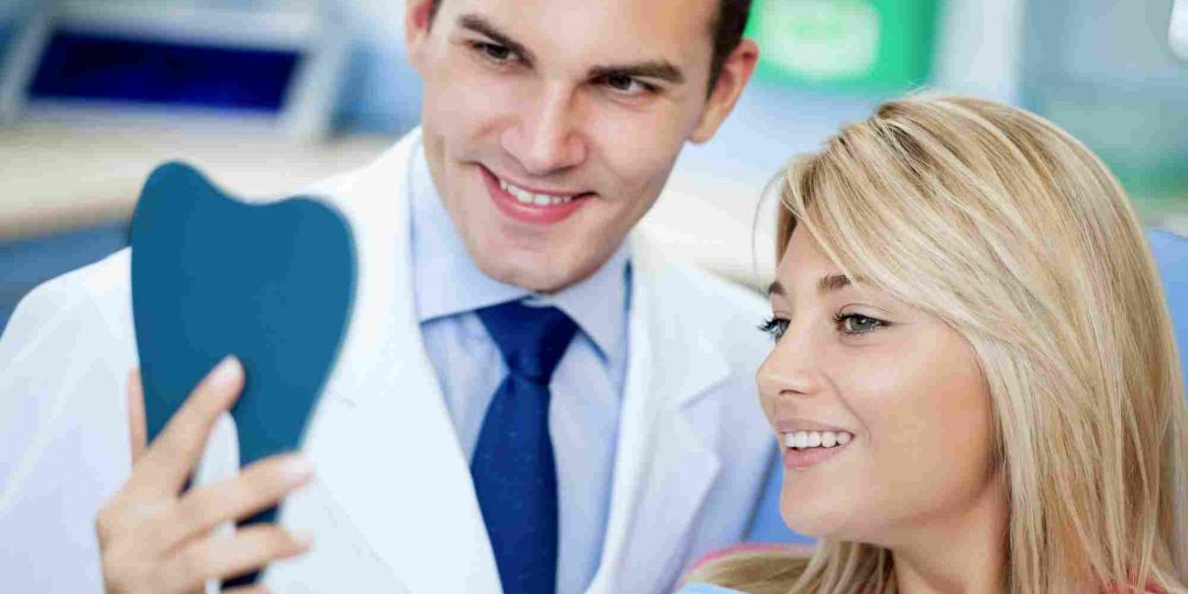 dentist and patient looking in handheld mirror